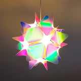 Ceiling view of a pink and blue iridescent spherical lampshade with a bright light on.